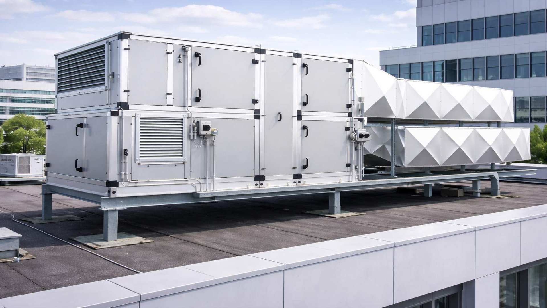 Plano aproximado de una unidad de tratamiento de aire con conductos de ventilación en la azotea de un edificio de oficinas.